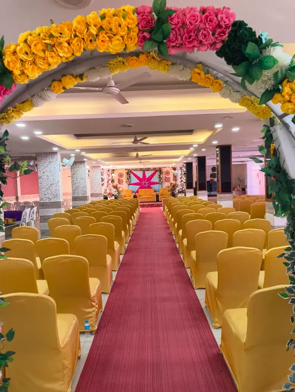 Floral welcome arch opening onto rows of gold chairs in the banquet hall