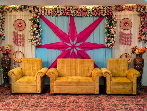 Wedding stage with pink starburst backdrop and gold sofa seating