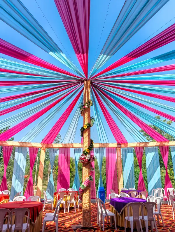 Outdoor canopy with pink and teal drapes over banquet seating