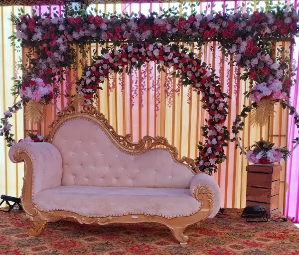 Elegant cream and gold wedding sofa with a floral backdrop