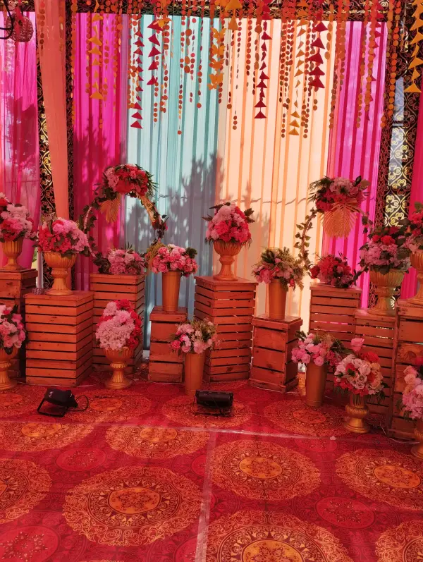 Wedding stage with pink and teal drapes and flower arrangements