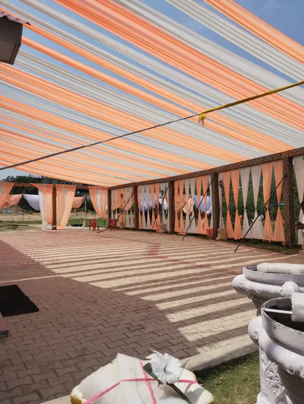 Outdoor venue lawn under a striped canopy