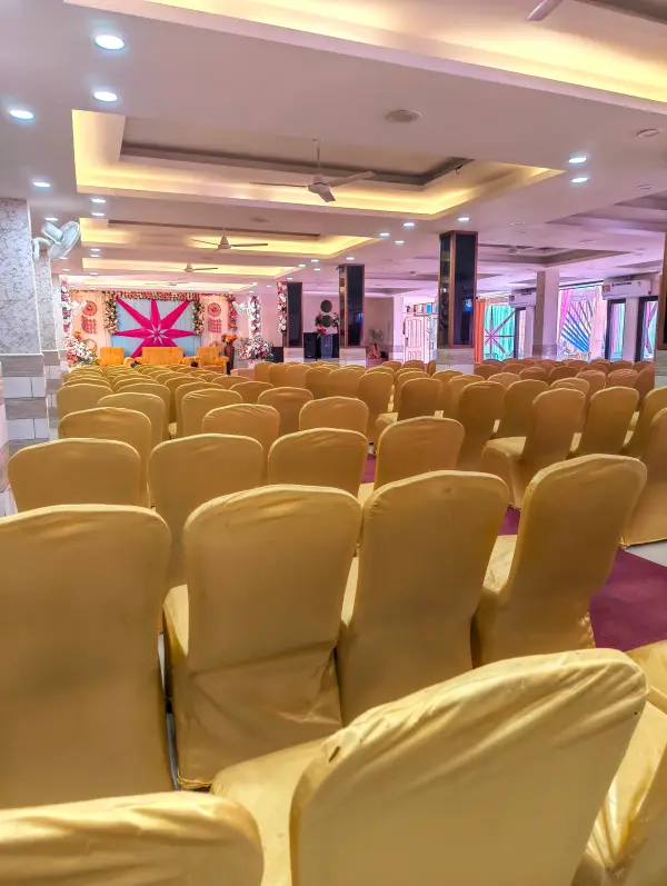Air-conditioned banquet hall set with rows of gold chairs facing a starburst stage